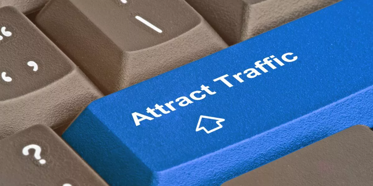 Close-up van een toetsenbord met een blauwe 'Attract Traffic'-toets, symbolisch voor strategieën ter verbetering van online vindbaarheid.