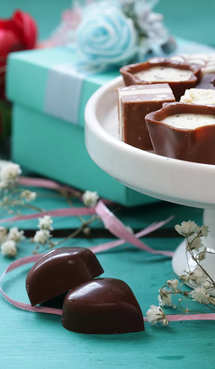 Exclusieve chocoladebonbons op turquoise achtergrond naast geschenkdoos, accent op verfijnde cadeauopties